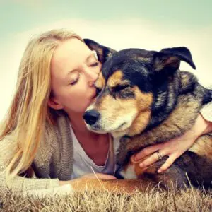 A woman kissing her dog on the nose.