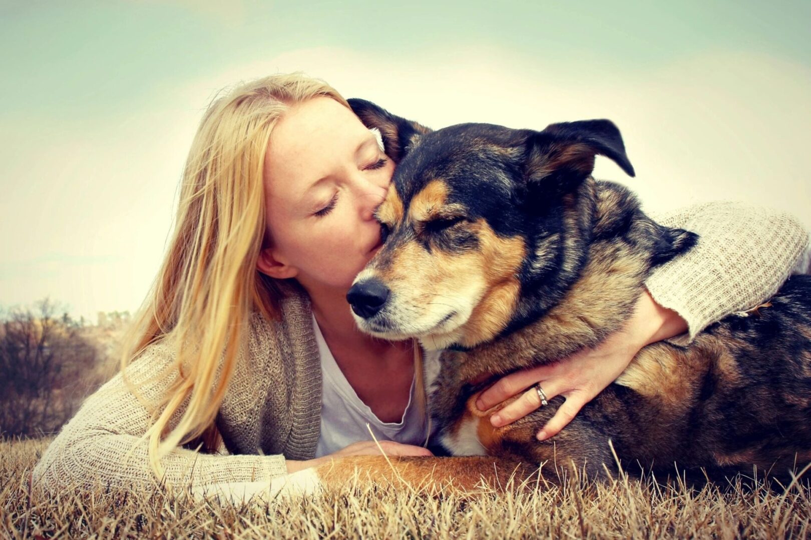 A woman kissing her dog on the nose.