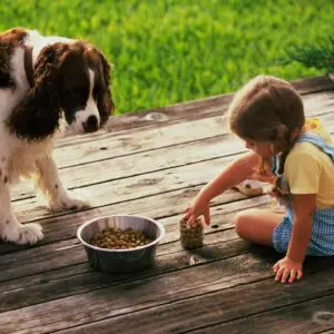 A small child and dog are eating food.